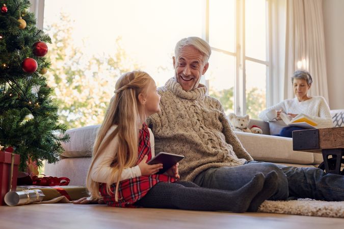 Mature man and granddaughter with digital tablet at home