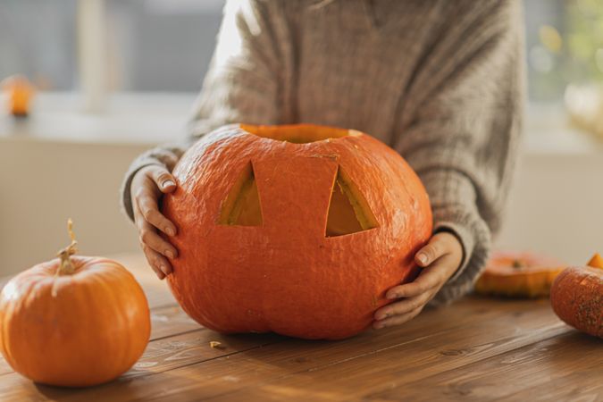 Person holding carved pumpkin