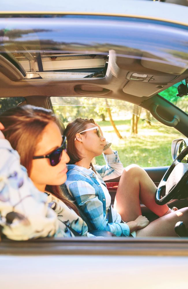 Two young women resting sitting inside of parked car