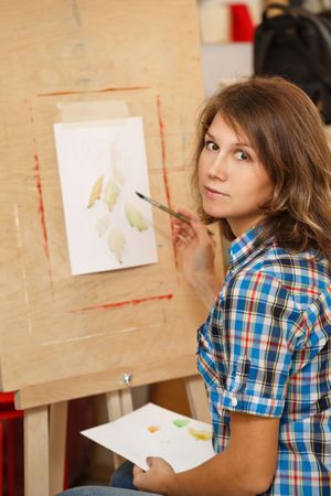 Woman looking back after testing watercolors on an easel