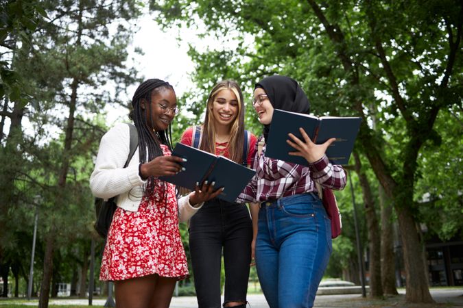 Happy group of female students looking through textbooks on campus
