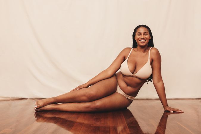 Happy woman smiling cheerfully while lounging on the floor in a studio