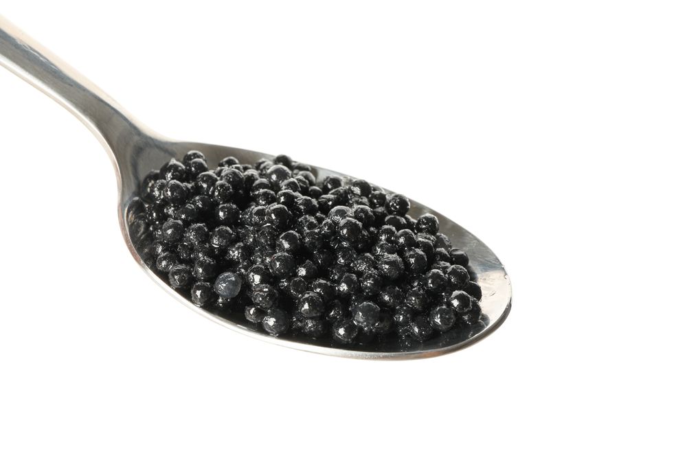 Spoon with caviar isolated on plain background