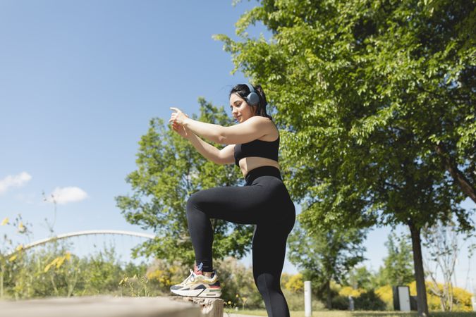 A young woman performs exercises to strengthen legs and buttocks, in a bench, during a sunny day, Zaragoza, Spain