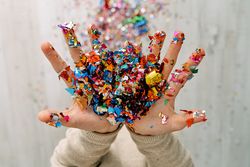 Child with multicolored confetti in hands