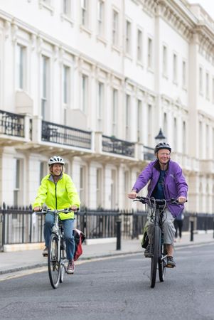 Two smiling women riding cyclists through town