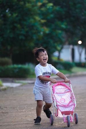 Young boy playing with pink baby stroller