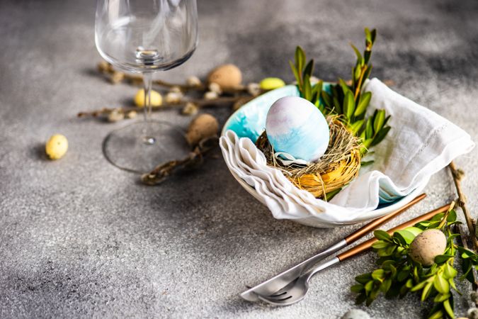 Easter table setting with glassware next to decorative egg in nest