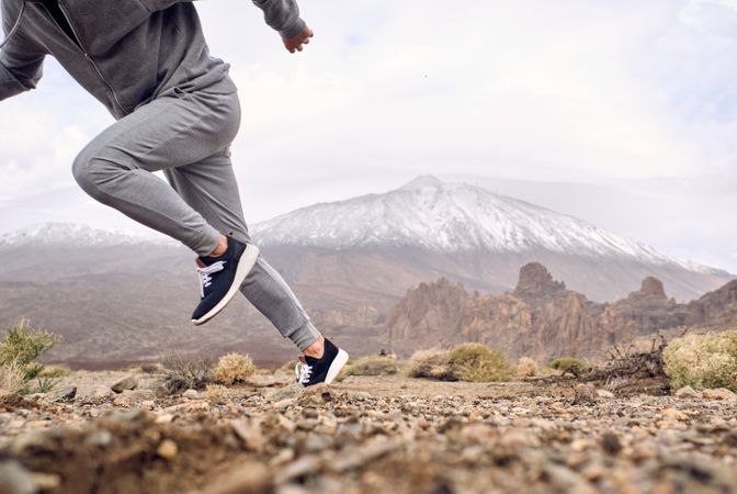 Crop athlete running along mountain path