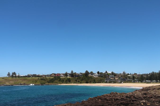 Coastal view showcasing a quiet beach and homes near the water under a clear blue sky