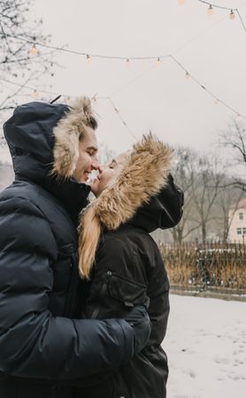 Smiling couple having fun on street near tree with fairy lights