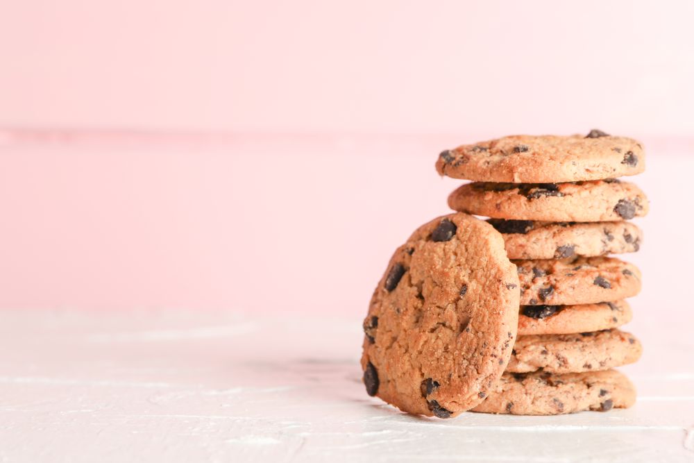 Stack of tasty chocolate chip cookies on wooden background. Space for text