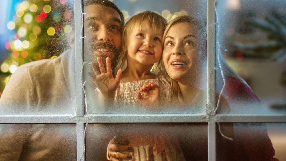 On Christmas Eve Father, Mother and Their Cute Daughter Looks Through the Snowy, Frozen Window and Smile.