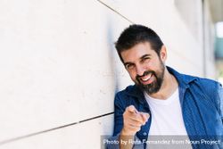 Man in denim standing outside smiling and pointing at camera 43Z1R5