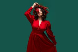 Playful woman holding Christmas ornament above her face.