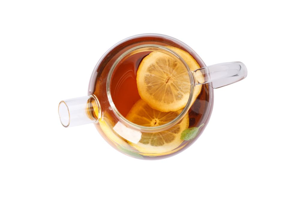 Glass teapot with lemon slices isolated on blank background
