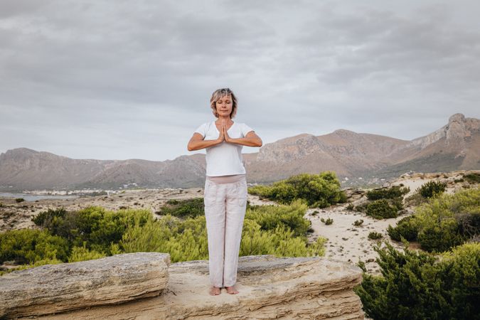 Barefoot woman meditating on stone