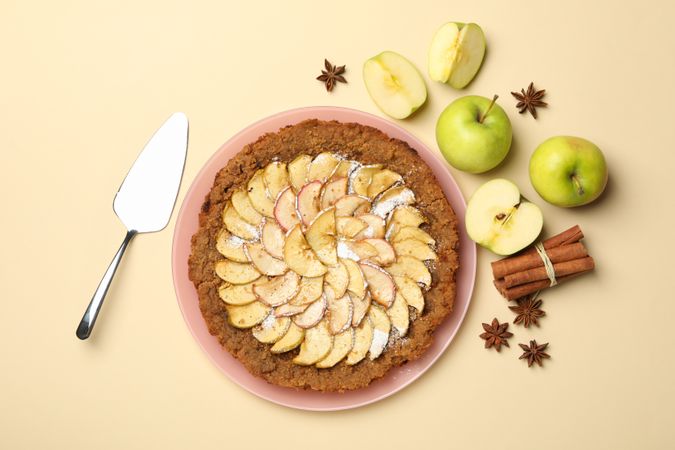 Composition with apple pie and ingredients on beige background, top view