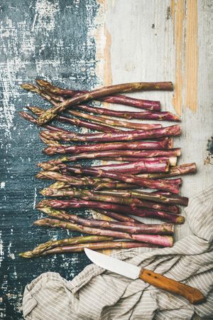 Scattered pieces of washed purple asparagus, on painted wood