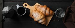 Wide shot of composition with croissants on wooden breadboard, top view