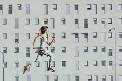 Woman in sportswear jumping near building