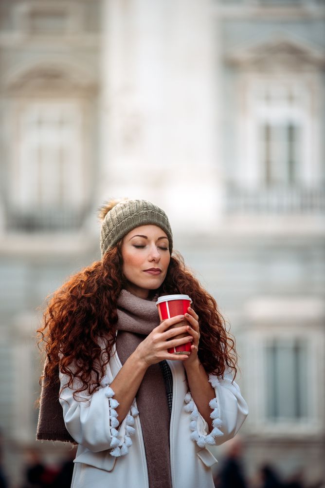Woman drinking coffee wandering in the streets of Madrid on winter