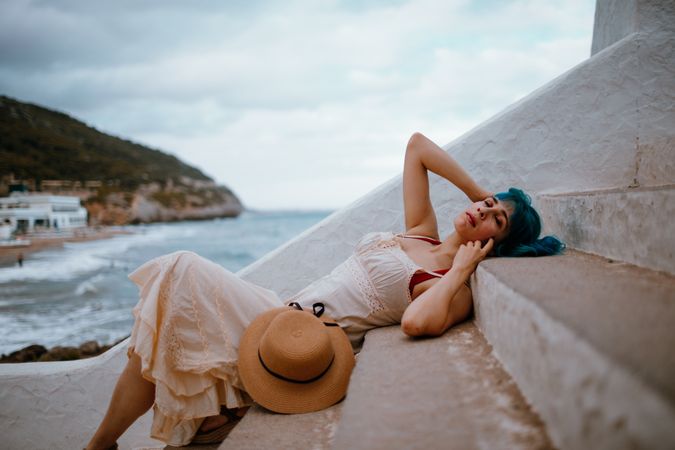 Sensual woman in sundress lying on pier stairs