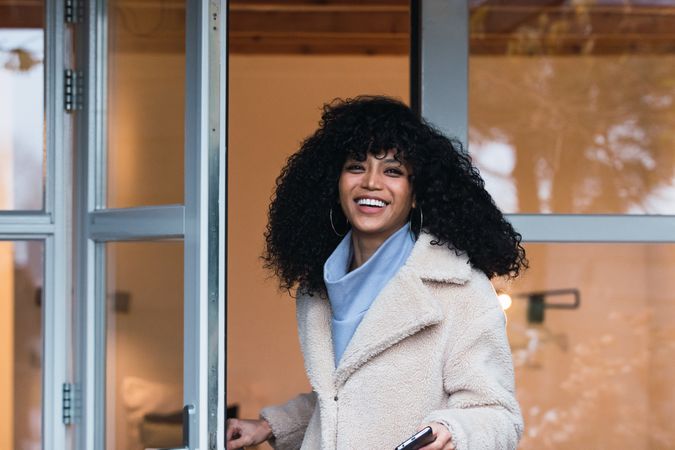 Happy Black woman standing in doorway of house
