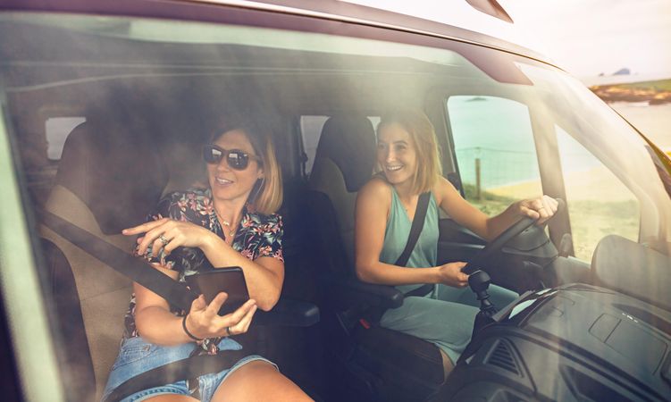 Woman driving a motorhome with her female friend in passenger seat pointing to view outside