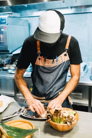 Chef with mask putting plate together in kitchen