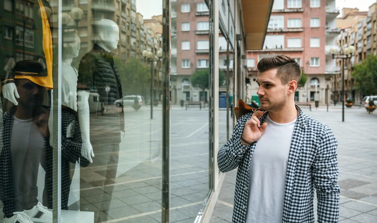Young man looking at the showcase of a store