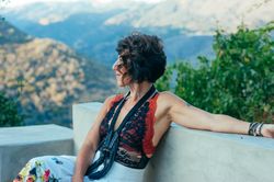 Stylish woman sitting outside on a bench looking at view of mountains