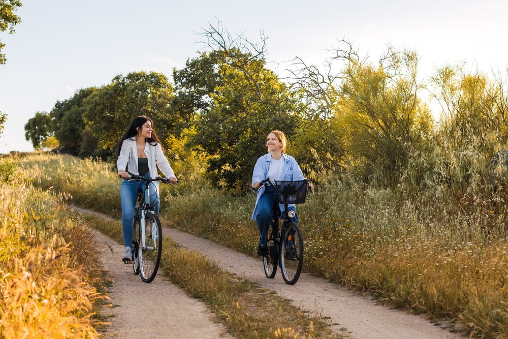 two young women cycling and having fun in a field