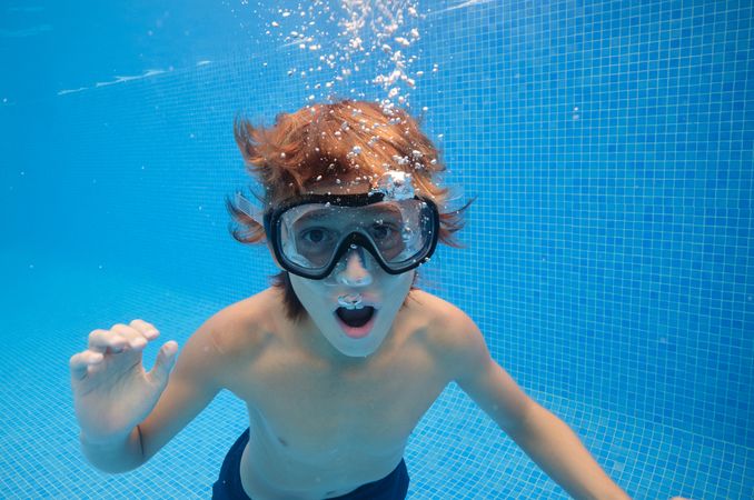 Boy with mouth opened swimming in pool