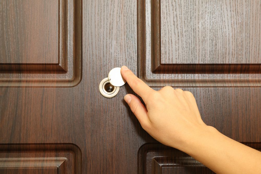 Woman hand hold peephole of wooden door