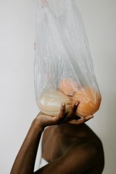 Woman holding bag of fruit in front of her head