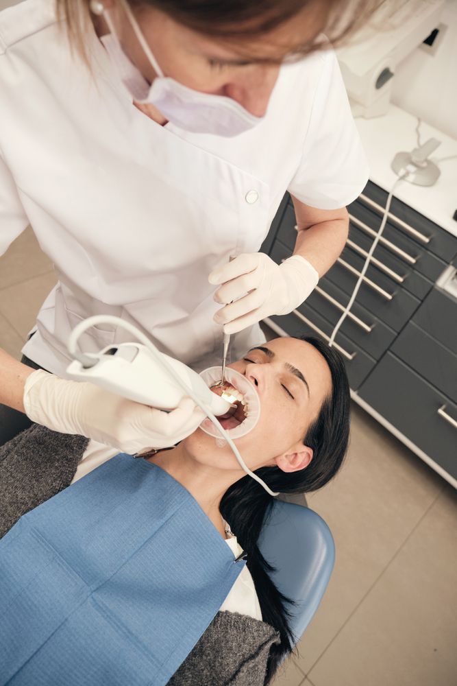 Female doctor examining teeth of patient with 3D scanner