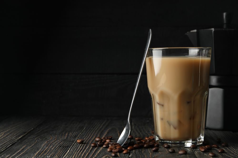 Composition with ice coffee and coffee seeds on wooden background