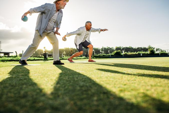 People playing a game of boules in a lawn with sun in the background