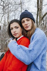 Smiling women in sweaters hugging in park