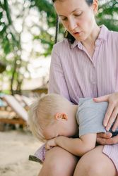 Joyful kid swinging with mother against blurred seascape