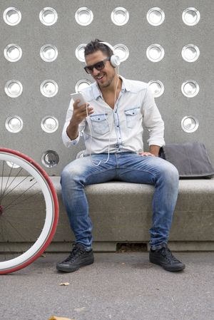 Male listening to something amusing on phone while sitting with bike
