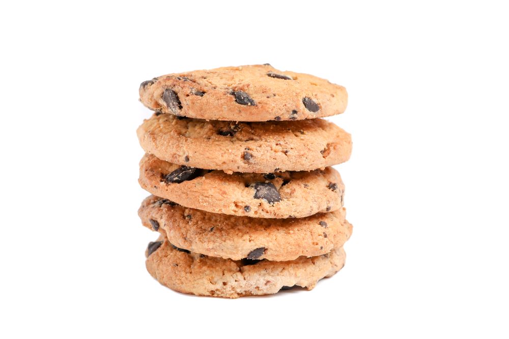 Stack of tasty chocolate chip cookies on plain background