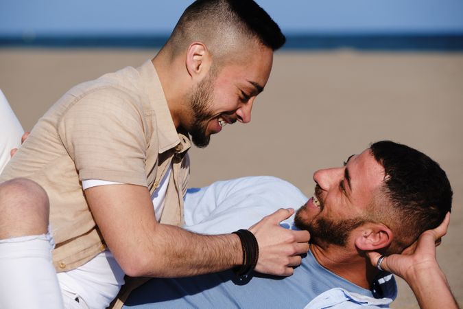Affectionate gay couple relaxing on beach