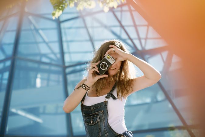 Creative woman taking photo on camera in sunny day