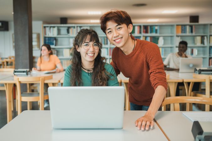 Multiracial teenagers using laptop during studies in library