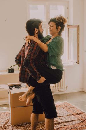 Happy couple embracing in room next to cardboard boxes