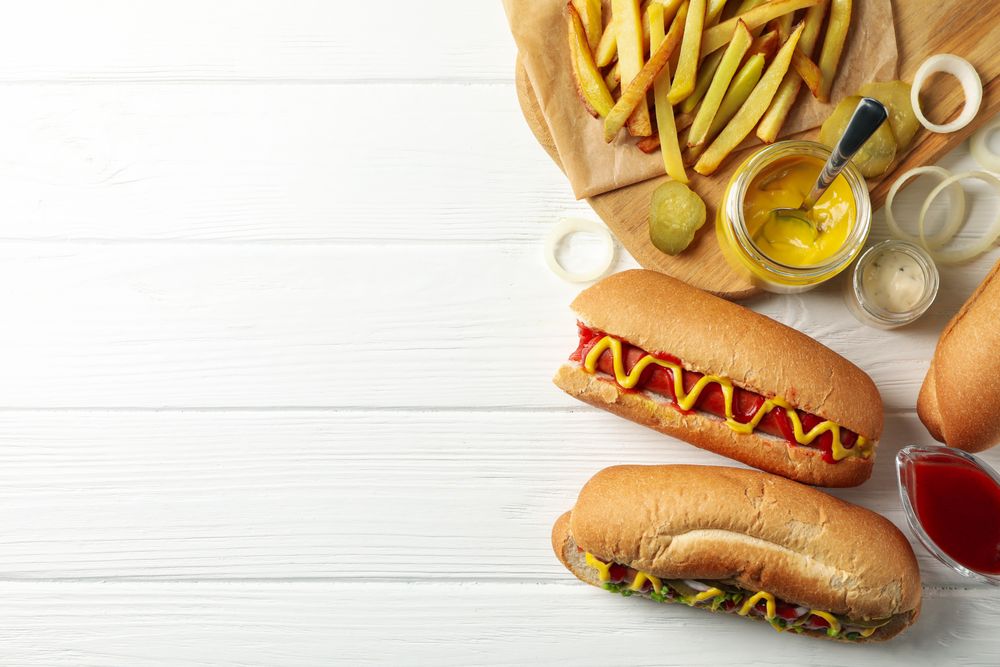Hot dogs, fries potato and sauces on plain wooden background