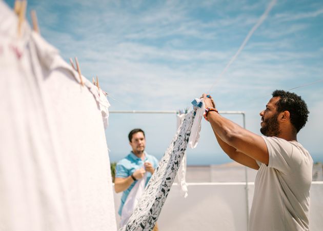 Multiracial men hanging clothes in bright day