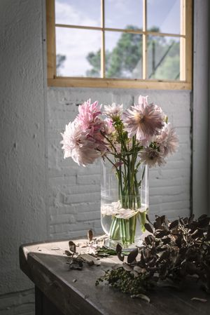 Bunch of plant in paper on table near stool in grey room